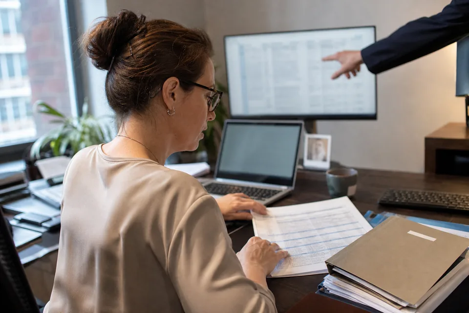 Law firm office manager planning a document system migration with a printed checklist and stacked client folders